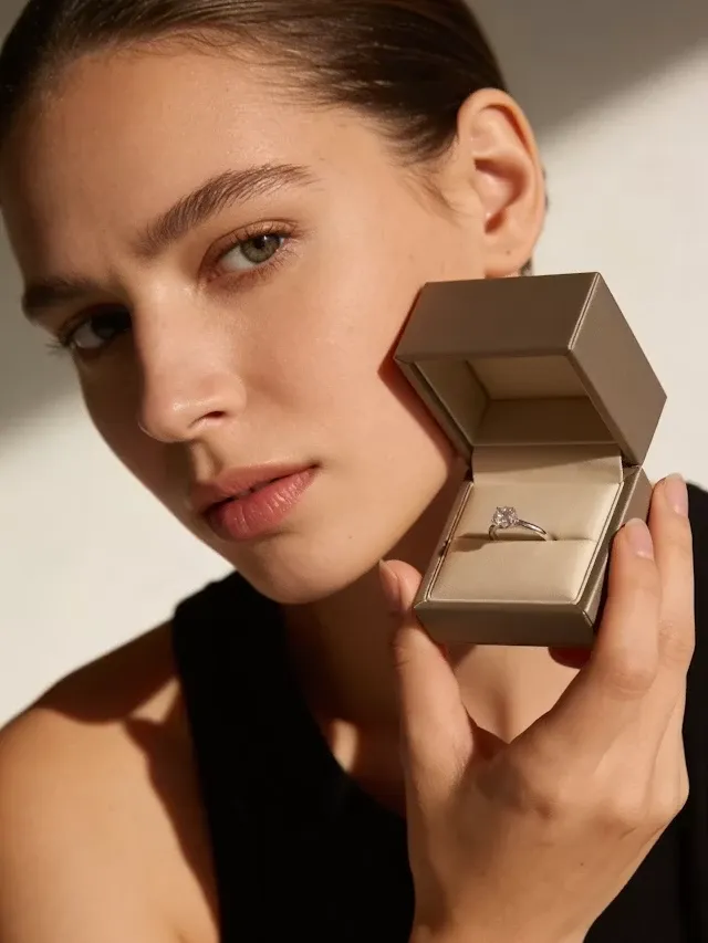 Model holding an open ring box to her cheek
