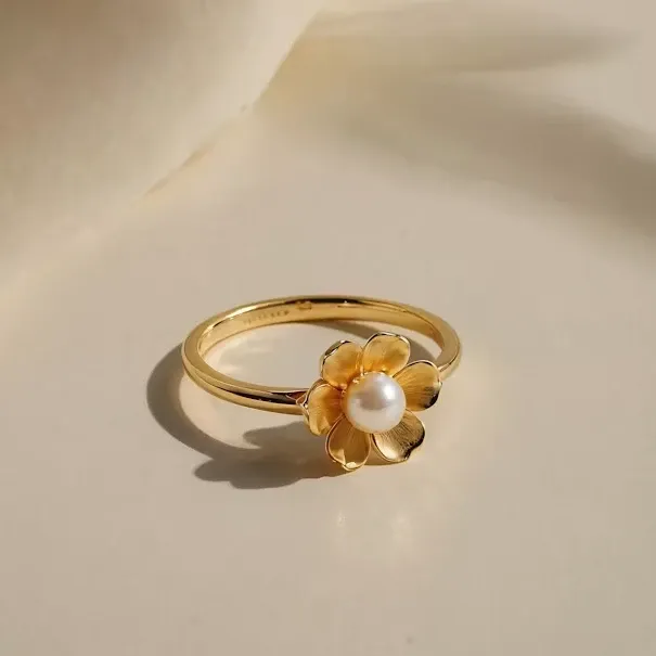 Gold flower ring with a pearl centre on ivory silk